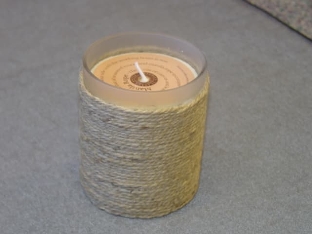 SCENTED CANDLE. MOULDED INTO A GLASS HOLDER, WITH A SCENTED CORD WRAPPED AROUND ITS OUTSIDE. HEIGHT 95 MM.