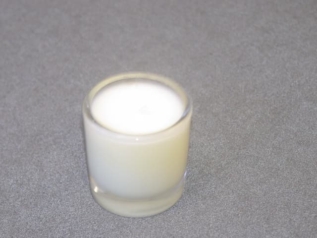 SCENTED CANDLE. MOULDED INTO A DECORATED GLASS HOLDER. HEIGHT 120 MM.