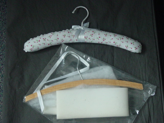 PADDED CLOTHES HANGER.  HANGER IS MADE OF WOOD WITH A METAL HOOK.  THE HANGER IS PADDED WITH WADDING AND COVERED WITH TEXTILE FABRIC. PACKAGED IN A POLY BAG FOR RETAIL SALE.