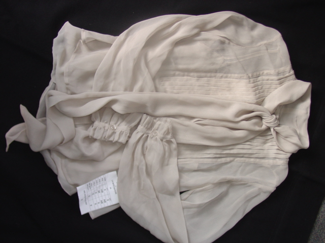 A WOVEN BLOUSE FOR WOMEN. DESIGNED TO COVER THE UPPER PART OF THE BODY FROM THE SHOULDERS TO THE HIPS.  WITH A FULL FRONT OPENING FASTENED WITH BUTTONS. WITH A LONG TIE FASTENING FROM THE COLLAR. WITH LONG SLEEVES WITH BUTTON FASTENING AT THE CUFFS. PRESENTED WITH A INNER VEST GARMENT WHICH IS ATTACHED WITH POPPERS AT THE SHOULDERS. CLASSIFIED SEPARATELY. 100 PER CENT SILK.