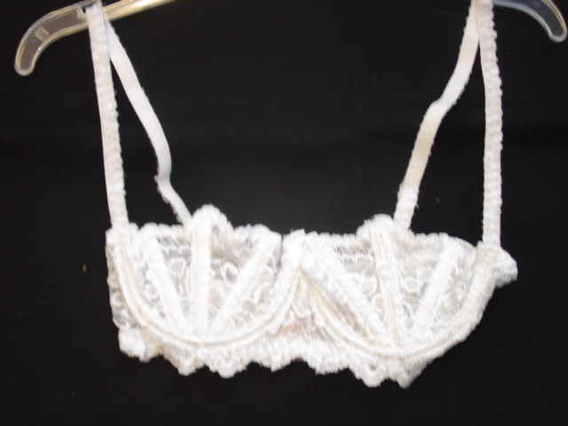 WOMENS BRASSIERE. DESIGNED TO COVER THE BREASTS. UNDERWIRED  WITH DECORATED BONING, THREE PER CUP. WITH ADJUSTABLE STRAPS. WITH HOOK AND EYE FASTENING AT BACK. OF FANCY DESIGN WITH BOW AND DIAMONTE STUD TO FRONT.  THE GARMENT IS MADE FROM 55 PERCENT POLYESTER AND 45 PERCENT NYLON. PRESENTED ON A PLASTIC HANGER.
