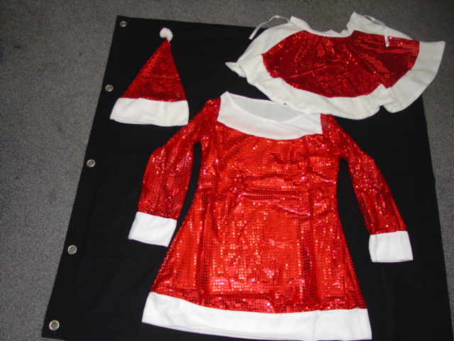 A KNITTED CAPE FOR UNISEX. DESIGNED TO COVER THE UPPER PART OF THE BODY, COVERING THE SHOULDERS TO THE BUST LINE. WITHOUT SLEEVES. WITH TIE FASTENING. DECORATED WITH SEQUINS. PART OF A MRS SANTA FANCY DRESS OUTFIT. 100 PER CENT POLYESTER. PACKAGED TOGETHER IN A PLASTIC BAG WITH A DRESS AND HAT WHICH HAVE BEEN CLASSIFIED SEPARATELY.