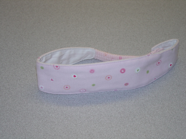 A KNITTED  HAIR BAND FOR BABIES. FULLY LINED. NARROWING AT THE BACK WITH ELASTICATION.  OF PRINTED COTTON. PRESENTED WITH A BABYGRO AND A SOFT TOY IN A SMALL CASE. ALL CLASSIFIED SEPARATELY. CROSS REF - 
17915759, 117908930 AND 117959045.