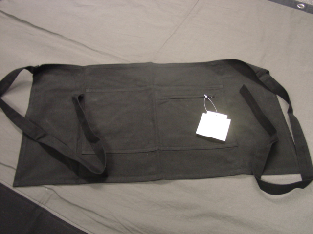 WOVEN BAR APRON FOR UNISEX.  REACHING FROM THE WAIST TO ABOVE THE KNEE.  HEMMED ON ALL EDGES. WITH SELF FABRIC TIES AT THE WAIST.  WITH TWO POCKETS ON CENTRE FRONT, ONE FASTENS BY ZIP. OF COTTON TWILL