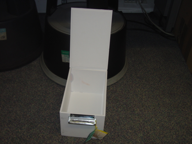 A PAPERBOARD STORAGE BOX WITH FLAP OPENING. WITH METAL LID FASTENER. WITH COMPANY NAME ON FASTENER. DIMENSIONS HEIGHT 12.5CM X LENGTH 22CM APPROX