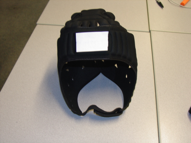 PROTECTIVE SPORTS HEAD GAURD MADE FROM 55 PERCENT EVA, 35 PERCENT NYLON AND 10 PERCENT POLYESTER. THE EVA IS COVERED WITH THE TEXTILE. BLACK IN COLOUR WITH LOGO TO TOP AND FRONT. WITH VELCRO CHIN STRAP AND ADJUSTABLE BACK FASTENING. SUPPLIED WITH A NET DRAWSTRING STORAGE BAG.