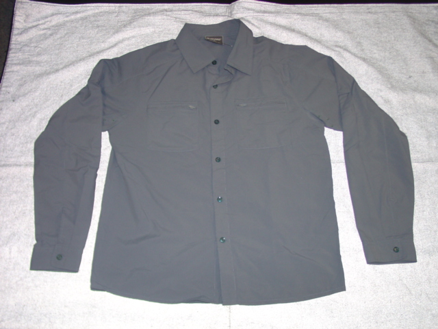 A WOVEN SHIRT FOR MEN. DESIGNED TO COVER THE UPPER PART OF THE BODY FROM THE SHOULDERS TO THE HIPS. WITH A COMPLETE FRONT OPENING WITH LEFT OVER RIGHT BUTTON FASTENING. WITH A COLLAR. WITH LONG SLEEVES. WITH TWO BREAST POCKETS WITH ZIP FASTENING. HEMMED. THE GARMENT IS MADE FROM 100 PER CENT NYLON.