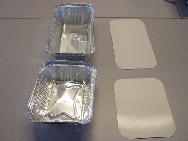 ALUMINIUM FOIL COOKING CONTAINERS MEASURING APPROXIMATELY 15CM X 12CM X 4.5CM AND 20CM X 10.5CM X 5.5CM WITH CARDBOARD BACKED ALUMINIUM FOIL LIDS.