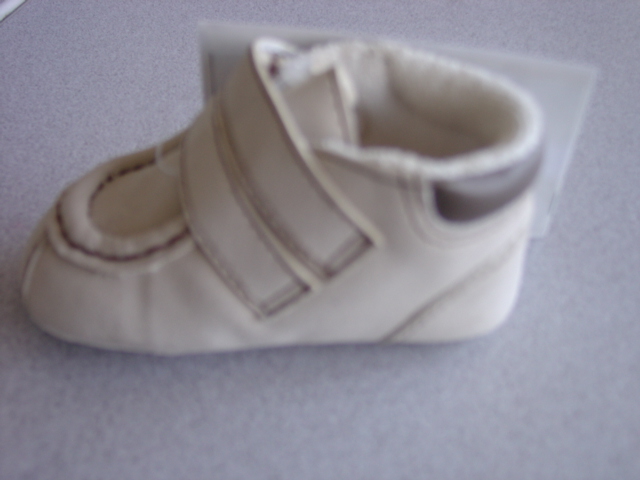 A LIGHT BROWN BABIES BOOT. WITH AN UPPER OF PLASTIC MOCK SUEDE AND OUTER SOLE OF TEXTILE AND PLASTIC PAW PRINT DESIGN WHERE THE TEXTILE PREDOMINATES. COVERING THE ANKLE. WITH TWO VELCRO FASTENING STRAPS OVER THE INSTEP. WITH A PAW MOTIF STITCHED TO THE ANKLE AREA.