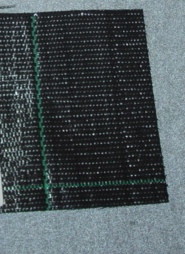 A WOVEN FABRIC CONSTRUCTED FROM STRIPS OF POLYPROPYLENE. THE INDIVIDUAL STRIPS ARE APPROXIMATELY 1MM IN WIDTH. THE FABRIC IS PRESENTED IN ROLLS OF 2.5 METRES WIDE. MAIN FABRIC COLOUR IS BLACK WITH OCCASIONAL WARP AND WEFT YARNS IN GREEN.