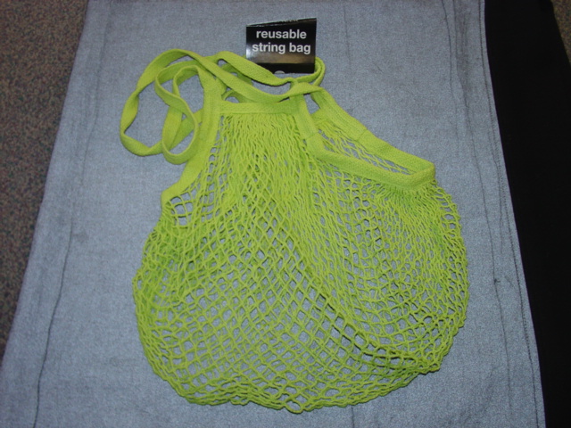 A REUSABLE KNITTED STRING BAG MADE FROM DURABLE 100 PER CENT ORGANIC COTTON. LIME GREEN IN COLOUR. TWO CARRYING HANDLES.