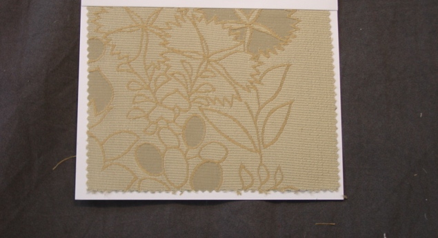 A WOVEN JACQUARD FABRIC MADE FROM 100 PER CENT UNBLEACHED CREPES SILK WEIGHING 183 G/M2 AND 134CM WIDE. CONSTRUCTED FROM YARNS OF DIFFERENT COLOURS. TAUPE WITH A GOLD DESIGN  IN COLOUR