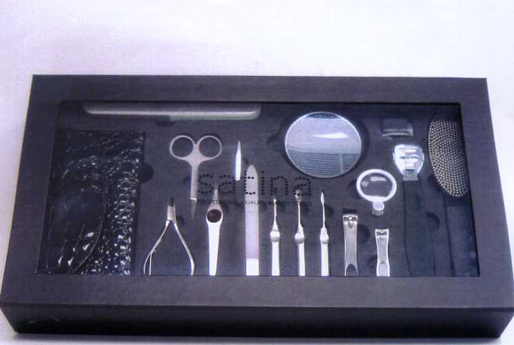 A FIFTEEN PIECE MANICURE AND PEDICURE SET. THE SET CONSISTS OF  A DUAL SIDED FILE AND FOOT BUFFER, CALLUS SHAVER WITH THREE EXTRA REFILL BLADES, FINGER AND TOE NAIL CLIPPERS, STEEL CUTICLE REMOVER, A PUSHER AND NAIL CLEANER, GLASS NAIL FILE, STAINLESS STEEL TWEEZERS, NAIL SCISSORS AND CUTICLE NIPPERS, A FOUR STEP NAIL BUFFER BLOCK, A MAGNIFYING GLASS ATTACHMENT AND A MAGNETIC MAGNIFYING MIRROR AND A FAUX LEATHER IMPLEMENTS CASE. PACKAGED TOGETHER IN A BLACK WINDOW GIFT BOX MADE FROM RECYCLABLE PAPER BOARD.