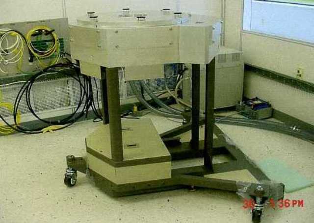 HANDLER FOR TRANSPORTING PRODUCTION WAFERS. THE HANDLER TRANSPORTS THE WAFERS TO AND FROM PRODUCTION MODULES, WHICH  ARE FIXED TO THE HANDLER UNDER VACUUM CONDITIONS.IT IS PART OF  HANDLER PLATFORM USED IN VOLUME PRODUCTION ORIENTED SYSTEMS IN THE SEMICONDUCTOR MANUFACTURING INDUSTRY.THE APPARATUS HAS A ROUGHLY TRIANGULAR, THREE WHEELED BASE FROM  WHICH FOUR UPRIGHT POSTS SUPPORT THE WAFER HANDLING SECTION.