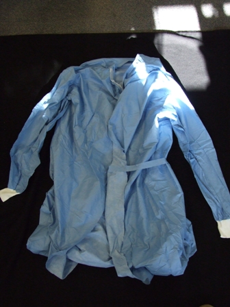 SURGICAL GOWN FOR USE IN HOSPITALS. DESIGNED TO COVER THE BODY FROM THE SHOULDERS TO JUST BELOW THE KNEE. WITH A COMPLETE OPENING AT THE BACK WITH VELCRO FASTENING AT THE NECK AND TIE FASTENING AT THE WAIST. WITH LONG SLEEVES WITH ELASTICATED CUFFS.  MADE FROM NONWOVEN 55 PER CENT CELLULOSE FIBRES (PAPER) AND 45 PER CENT POLYESTER FIBRES. FLUID REPELLENT. DISPOSABLE AFTER USE.