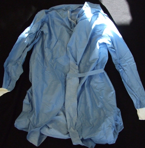 SURGICAL GOWN FOR USE IN HOSPITALS. DESIGNED TO COVER THE BODY FROM THE SHOULDERS TO JUST BELOW THE KNEE. WITH A COMPLETE OPENING AT THE BACK WITH VELCRO FASTENING AT THE NECK AND TIE FASTENING AT THE WAIST. WITH LONG SLEEVES WITH ELASTICATED CUFFS.  MADE FROM NON-WOVEN 55 PER CENT CELLULOSE FIBRES (PAPER) AND 45 PER CENT POLYESTER FIBRES. FLUID REPELLENT. DISPOSABLE AFTER USE.