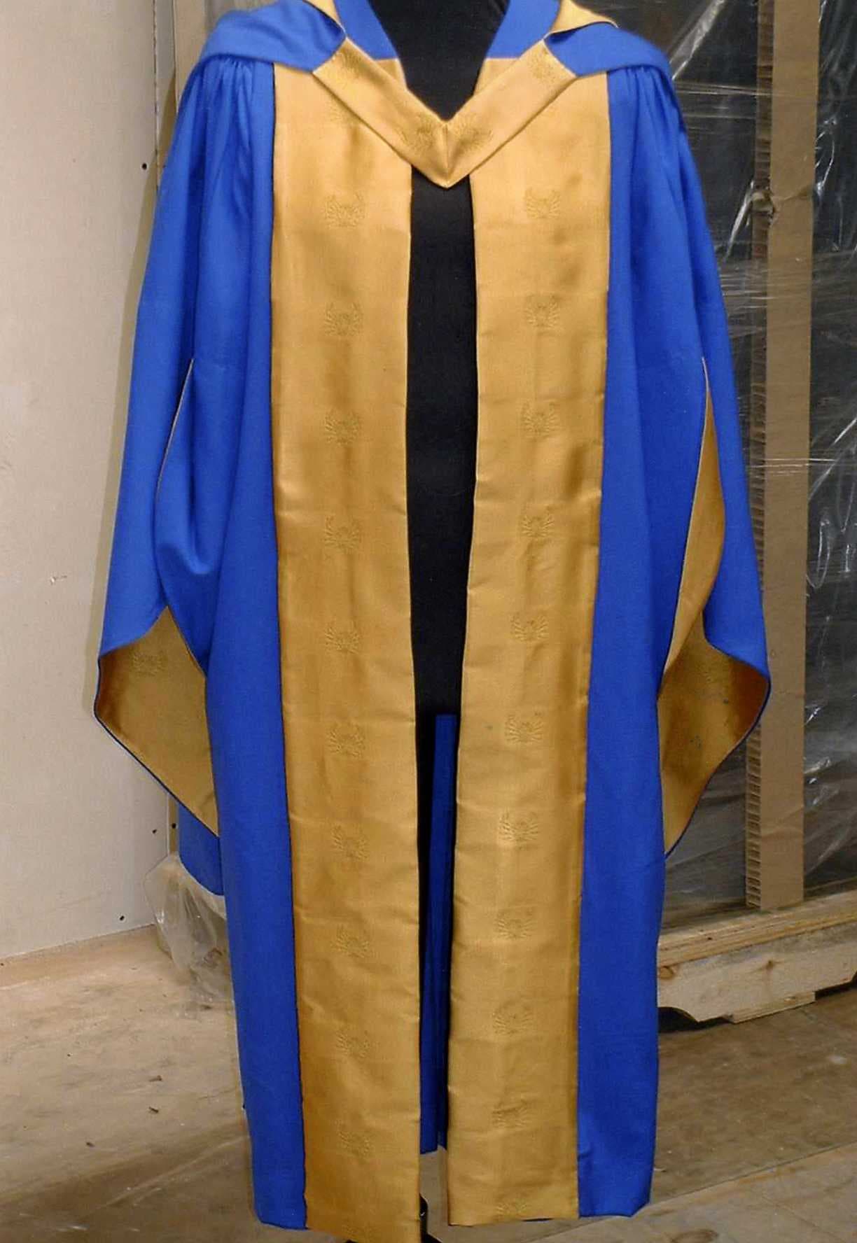 A WOVEN CEREMONIAL AND OR OCCUPATIONAL SCHOLASTIC GOWN FOR UNISEX. DESIGNED TO BE WORN OVER CLOTHING COVERING THE WHOLE OF THE BODY FROM THE SHOULDERS TO BELOW THE THIGH. THE GARMENT HAS A FULL FRONTAL OPENING. WITHOUT FASTENINGS. WITH SLEEVES. HEMMED. THE BODY IS MADE UP OF PANELS ATTACHED TO A YOKE AT THE BACK. THE GARMENT IS MADE FROM 100 PER CENT WOOL.