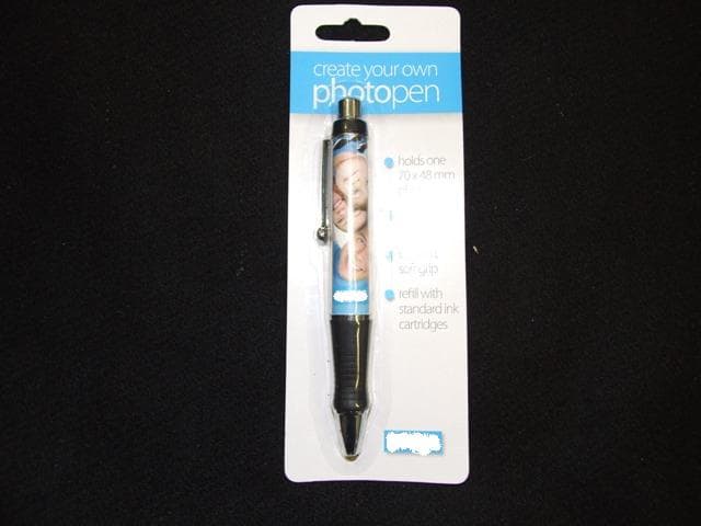 REFILLABLE RETRACTABLE BALL POINT PEN. MADE FROM PLASTIC AND METAL. A 70MM X 48MM PHOTOGRAPH CAN BE INSERTED INTO THE BODY OF THE PEN.  WITH SOFT COMFORT GRIP AND CLIP