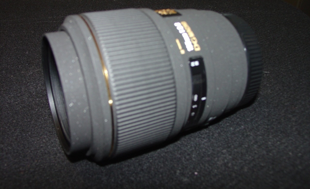 AN OBJECTIVE LENS FOR A PHOTOGRAPHIC CAMERA. OF GLASS, METAL AND PLASTIC. WITH A  FIXED FOCAL LENGTH OF 105MM AND A FRONT DIAMETER OF 58MM AND OVERALL DIAMETER OF 74MM. WITH REMOVABLE PLASTIC LENS CAPS. LENS LENGTH 97.5 MM. WEIGHT 460G.