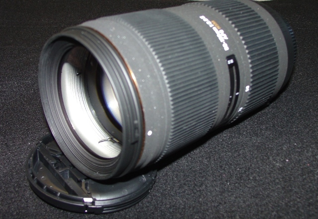 AN OBJECTIVE LENS FOR A PHOTOGRAPHIC CAMERA. OF GLASS, METAL AND PLASTIC. WITH AN ADJUSTABLE FOCAL LENGTH BETWEEN 50 AND 150 MM AND A FRONT DIAMETER OF 67MM. WITH REMOVABLE PLASTIC LENS CAPS. LENS LENGTH 135 MM. WEIGHT 770G.
