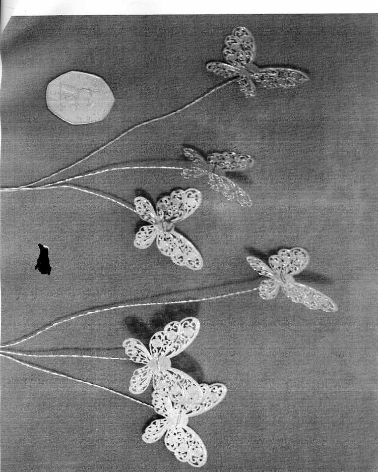 ORNAMENTAL ARTICLE. BUTTERFLY DECORATION. INCORPORATES A LONG STEEL WIRE STEM WITH 3 STEEL WIRE BUTTERFLIES  ATTACHED TO THE STEM BY 3 LENGTHS OF WIRE WHICH ARE COVERED IN NYLON TEXTILE NETTING. PLASTIC BEADS COVER THE ANTENNAS.DESIGNED FOR USE IN BOUQUETS, TABLE DECORATIONS AND TIARAS. MEASURES APPROX 21CMS (L).