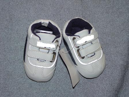 BABIES TRAINER STYLE INDOOR SHOE, FOR UP TO 3 MONTHS. WITH UPPERS OF PLASTIC.  WITH VELCRO STRAP FASTENING. WITH EMBROIDERED LOGO ON STRAPS. OUTER SOLES OF TEXTILE MATERIAL WITH RAISED PLASTIC DOTS. TEXTILE IS PREDOMINANT MATERIAL IN CONTACT WITH THE GROUND. WHITE IN COLOUR WITH BLACK TRIM.  PRESENTED ON A LITTLE PLASTIC HANGER WITH CARD LABEL