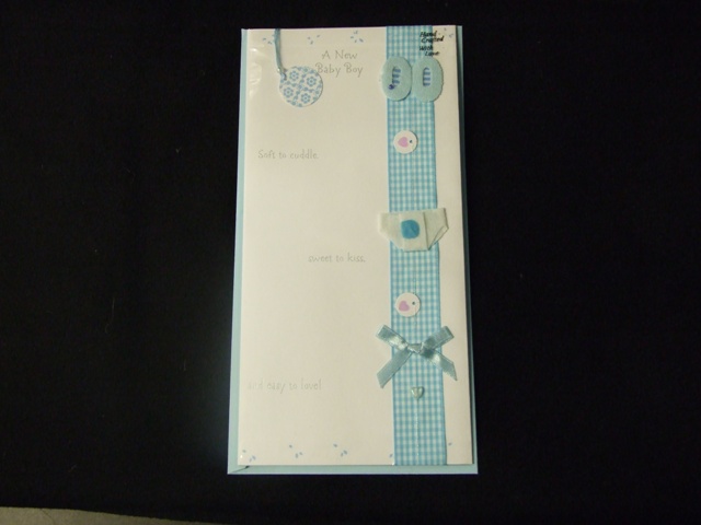 PRINTED PAPERBOARD NEW BABY CARD. WITH PRINTED  PICTURE ON FRONT OF CARD. WITH APPLIED TEXTILE RIBBON DECORATED FOR A NEW BORN BABY WITH A SMALL TEXTILE RIBBON, NAPPY AND THE NUMBERS ZERO ZERO. PRINTED GREETING ON FRONT OF CARD AND PRINTED MESSAGE INSIDE.WITH ATTACHED DECORATIVE TAG ON FRONT OF CARD.WITH ENVELOPE. PACKAGED FOR RETAIL SALE IN A PLASTIC PRINTED SLEEVE.