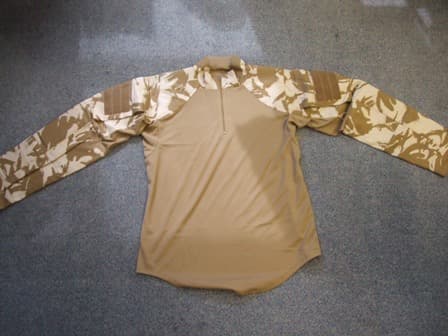 WOVEN SHIRT-BLOUSE FOR UNISEX. REACHING DOWN TO BELOW THE WAIST.  ROUND NECK WITH  COLLAR.  PARTIAL FRONT OPENING FASTENED BY ZIP.  LONG SLEEVES WITH BUTTON TAB FASTENING AT SLEEVE ENDS.  WITH LARGE POCKETS ON UPPER SLEEVES FASTENED BY VELCO FLAP WITH PATCHES OF VELCRO ON OUTER SURFACE. THE SHOULDERS AND LOWER PART OF THE SLEEVES ARE INTERNALLY PADDED WITH REMOVEABLE NEOPRENE PADS.  THE GARMENT IS HEMMED AT THE BASE.  THE MAIN PART OF THE BODY IS MADE FROM KNITTED POLYESTER WITH THE SHOULDERS AND PADDED SLEEVES MADE FROM WOVEN FABRIC 70% COTTON AND 30% POLYESTER.