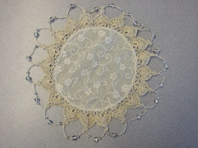 EMBROIDERED WOVEN DOILY/JUG COVER MADE FROM 100% COTTON WITH A DECOTAIVE CROCHETED EDGING DECORATED WITH GLASS BEADS. APPROX DIAMETER 200MM