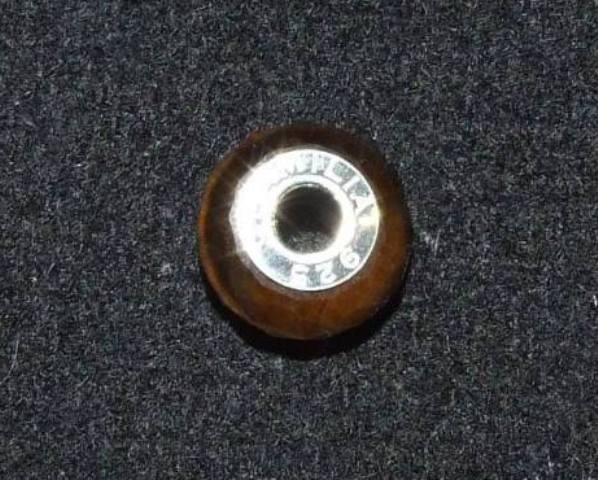 TIGERS EYE BEAD WITH A STERLING SILVER INSERT. THE THREADING HOLE IN THE BEAD IS LINED WITH STERLING SILVER, THIS IS CALLED THE INSERT. THE BEAD  IS DESIGNED TO BE THREADED ONTO A FLEXIBLE BRACELET ALONG WITH OTHER SIMILAR BEADS OR CHARMS IN COLOURS OR DESIGNS OF THE WEARERS CHOICE. DIMENSIONS,  APPROXIMATELY 14MM IN DIAMETER.