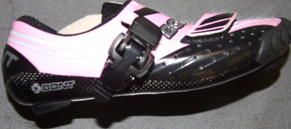 A CYCLING SHOE. THE SHOE IS MADE FROM THE INSIDE OUT. EVERYTHING IS LAMINATED TOGETHER BY THE EPOXY RESIN SO IT FORMS A MONOCOQUE. CARBON FIBRE IS THEN HAND LAYED. AIRCRAFT GRADED CARBON IS WEAVED ON THE OUTSIDE AND UNDIRECTIONAL CARBON ON THE INSIDE. THE UNI DIRECTIONAL CARBON HAS ONLY HALF THE STRANDS OF CROSS WEAVE CARBON. IT GIVES STRENGTH IN ONE DIRECTION SO IT SAVES WEIGHT BY USING LESS CARBON OF ABSORBING LESS RESIN. PINK AND BLACK IN COLOUR.