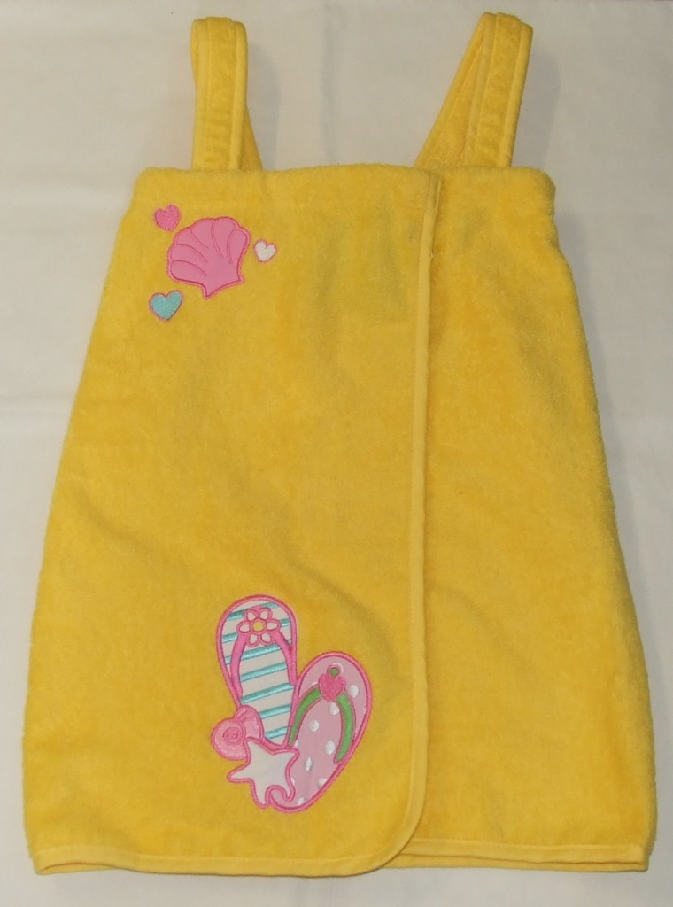 A GIRLS DRESS OF 100 PERT CENT COTTON WOVEN TERRY TOWELLING. OF A WRAP OVER DESIGN WITH SHOULDER STRAPS THE FRONT OPENING FROM TOP TO BASE OF DRESS IS FASTENED AT THE TOP WITH TWO PLASTIC PRESS FASTENERS. HAVING AN EMBROIDERED AND APPLIED DESIGN AT THE TOP RIGHT AND BOTTOM RIGHT OF FRONT.
