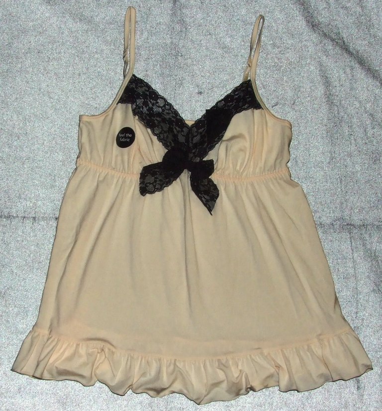 LADIES CAMISOLE AND SHORTS PYJAMA SET IN PALE PEACH.  MADE OF KNITTED TEXTILE, 60% POLYESTER / 36% VISCOSE / 4% ELASTINE.  DESIGN TO COVER THE BODY BETWEEN THE BUST AND THE UPPER THIGH.  CAMISOLE HAS A LACE TRIMMED, V-NECK WITH SHOESTRING STRAPS, IS GATHERED UNDER THE BUST AND HAS A FRILL ALONG THE LOWER EDGE.  THE SHORTS HAVE AN ELASTICATED WAIST, ARE 31 CM LONG (AT THE SIDE HEM) AND HAVE TWO DECORATIVE SLITS DECORATED WITH SMALL BOWS AT THE LOWER HEMMED EDGE.  SUPPLIED WITH CARDBOARD PRICE TAGS ATTACHED.