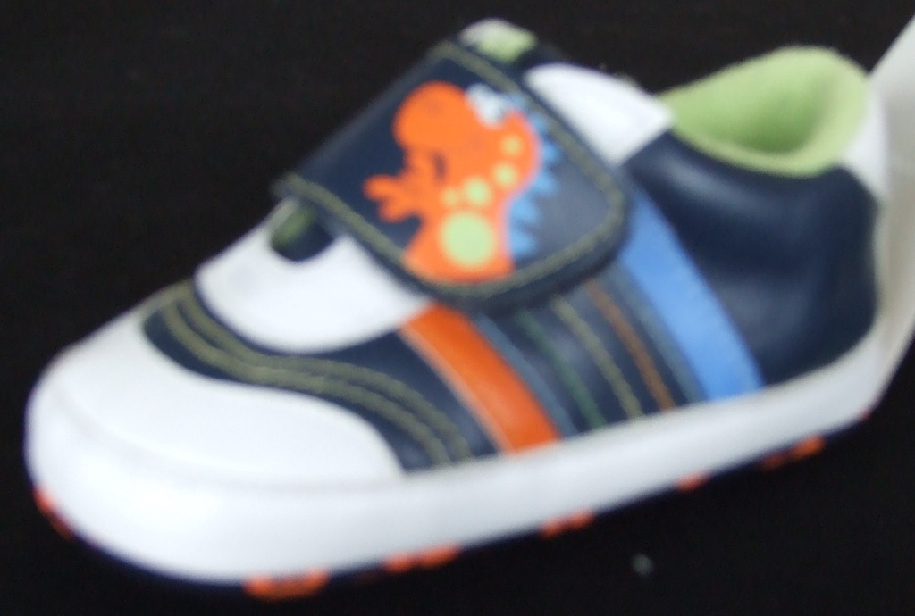INDOOR FOOTWEAR. BOOTEE IN THE STYLE OF A TRAINER DESIGNED FOR A BABY. WITH UPPERS OF PLASTIC (PU) AND OUTER SOLES OF TEXTILE WITH PLASTIC (PU) RAISED PRINT, WHERE THE TEXTILE PREDOMINATES. DOES NOT COVER THE ANKLE. WITH SINGLE VELCRO STRAP FASTENING WITH A PRINTED DINOSOUR FACE .