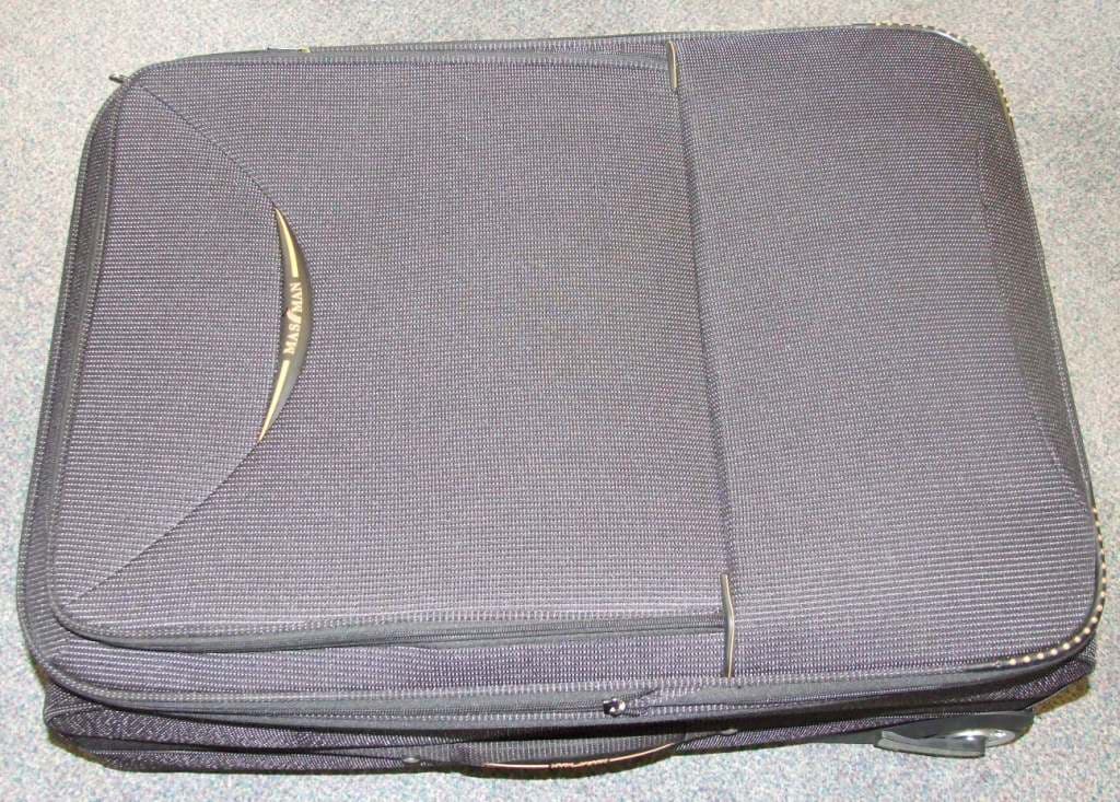 AN EXPANDING TROLLEY SUITCASE WITH AN OUTER SURFACE OF TEXTILE.  COLOUR: BLACK PIN-STRIPE WITH BLACK AND RED RUBBER TRIM.  LINED WITH GREY WOVEN TEXTILE.  WITH TWO HANDLES ON THE TOP - ONE FIXED FOR CARRYING AND ONE EXTENDIBLE FOR PULLING - AND ONE CARRY HANDLE ON THE SIDE, A LARGE POCKET ON THE FRONT, TWO SMALL PLASTIC WHEELS AND A SECTION TO INSERT AN ADDRESS LABEL ON THE REVERSE.  ALSO HAS TWO RETAINING STRAPS AND A NET POCKET INSIDE.  NOT HANDMADE.  DIMENSIONS: 70 X 50 X 28 CM (APPROX).
