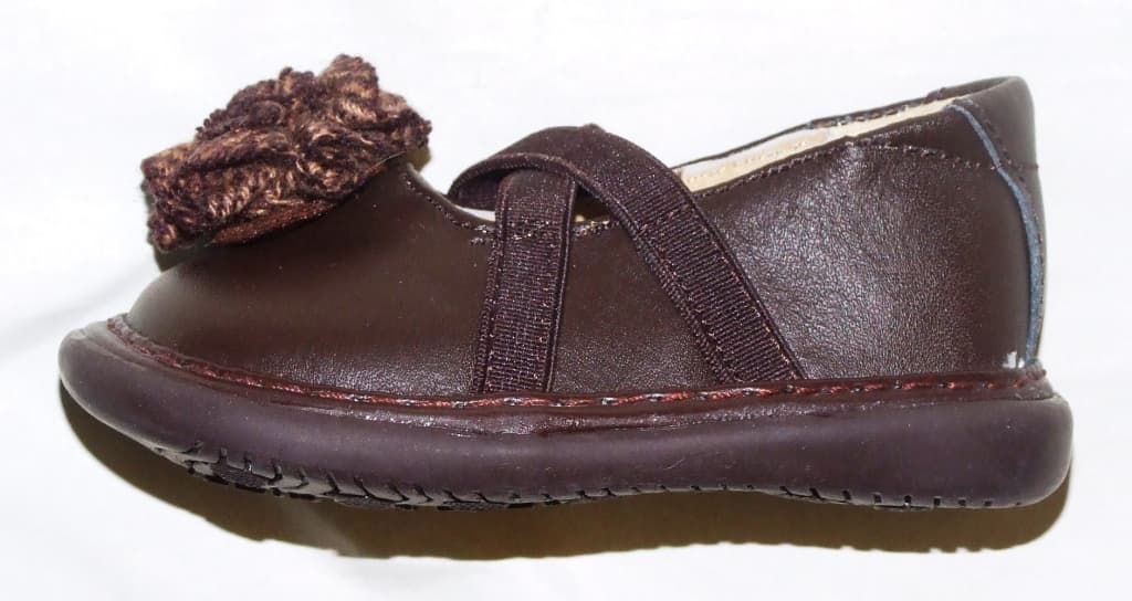 AN INFANT GIRLS CASUAL SHOE. UPPER IS OF BROWN LEATHER WITH A BROWN TEXTILE FLOWER AT THE FRONT. CROSS OVER ELASTIC STRAPS ACROSS THE FOOT. OUTER SOLE OF BROWN RUBBER. NOT COVERING THE ANKLE. IN-SOLE LENGTH IS LESS THAN 24 CMS.