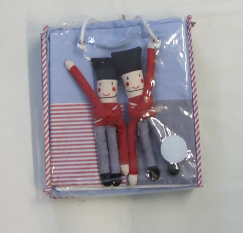 TAB TOP CURTAINS IN LIGHT BLUE MADE FROM WOVEN COTTON WITH TWO CURTAIN HOLDERS IN THE  SHAPE OF TOY SOLDIERS. PACKAGED FOR RETAIL SALE IN A CLEAR PLASTIC CARRY CASE WITH ZIP AND CARRY HANDLES AND WITH A GIFT TAG ATTACHED.