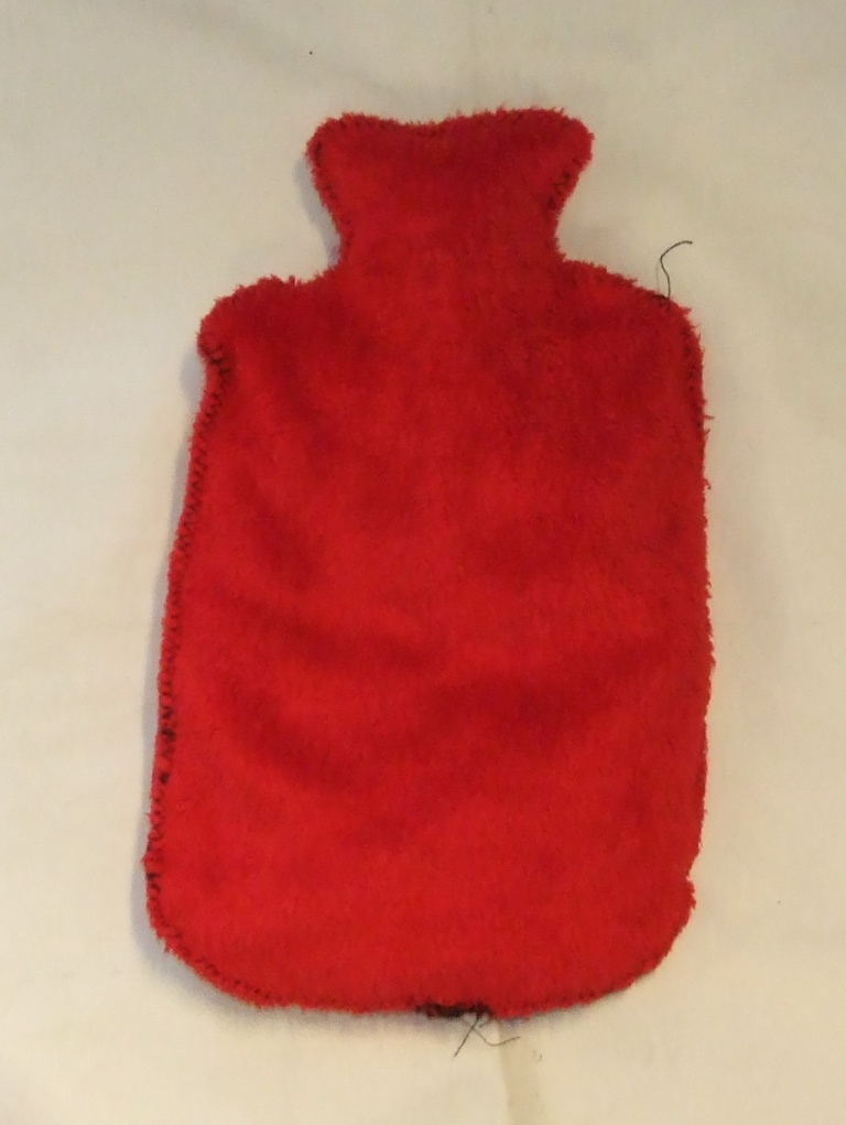 WHEAT FILLED BAG FOR USE AS A HOT WATER BOTTLE. FILLED WITH WHEAT BEADS. OUTER MADE FROM POLYESTER KNITTED. INNER CONSISTS OF WHEAT BEADS.