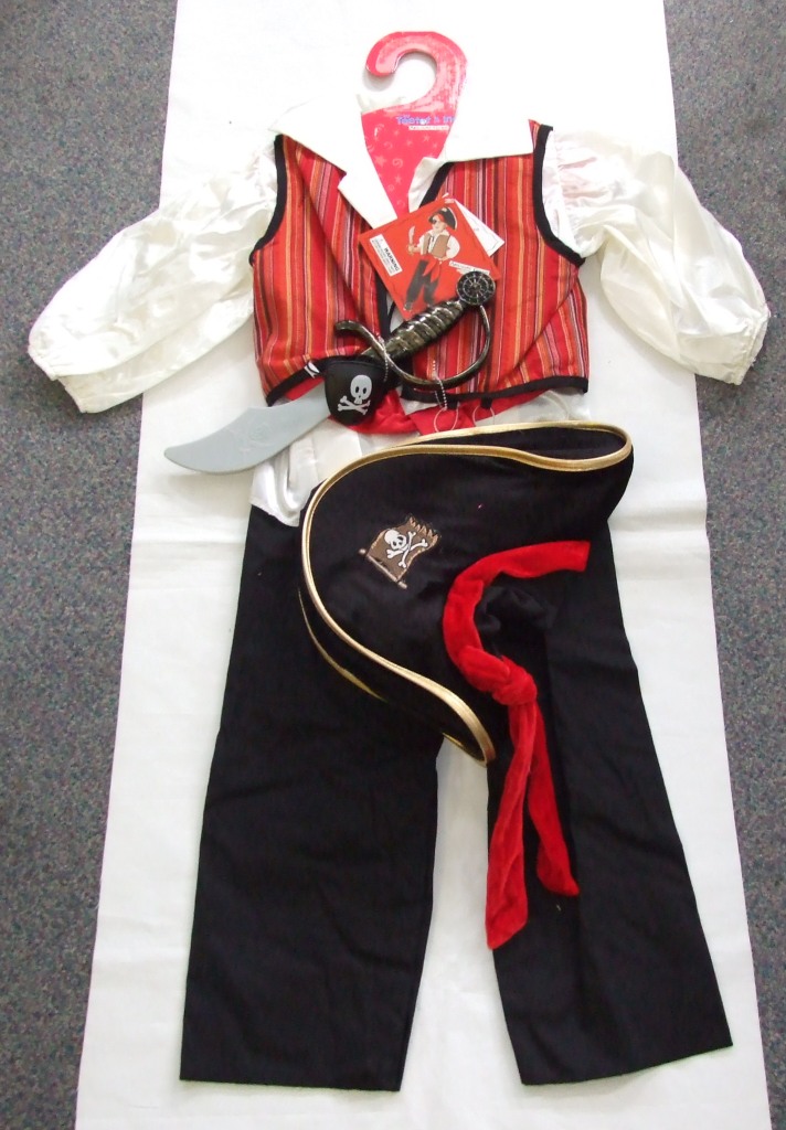 UNISEX WOVEN TROUSERS. PART OF A FANCY DRESS PIRATE OUTFIT FOR CHILDREN. MADE FROM COTTON. DESIGNED TO COVER THE LOWER PART OF THE BODY FROM THE WAIST TO THE ANKLES. ENVELOPING EACH LEG SEPARATELY. PULL ON IN DESIGN WITH ELASTICATED WAISTBAND AND NO FASTENING. HEMMED AT THE LEG ENDS. PRESENTED FOR RETAIL SALE ON A CARDBOARD HANGER WITH A TEXTILE SHIRT, WAISTCOAT, HAT AND SASH AND A PLASTIC CUTLASS AND EYE PATCH ALL CLASSIFIED SEPARATELY. WITH A PRINTED SWING TAG.