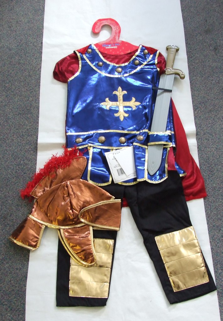 UNISEX WOVEN TROUSERS. PART OF A FANCY DRESS CENTURION OUTFIT FOR CHILDREN. MADE FROM COTTON. DESIGNED TO COVER THE LOWER PART OF THE BODY FROM THE WAIST TO THE ANKLES. ENVELOPING EACH LEG SEPARATELY. PULL ON IN DESIGN WITH ELASTICATED WAISTBAND AND NO FASTENING. HEMMED AT THE LEG ENDS. WITH GOLD COLOURED PATCHES TO THE FRONT OF EACH OF THE LEGS. PRESENTED FOR RETAIL SALE ON A CARDBOARD HANGER WITH A TEXTILE TUNIC, T SHIRT AND HAT AND A PLASTIC SWORD ALL CLASSIFIED SEPARATELY. WITH A PRINTED SWING TAG.