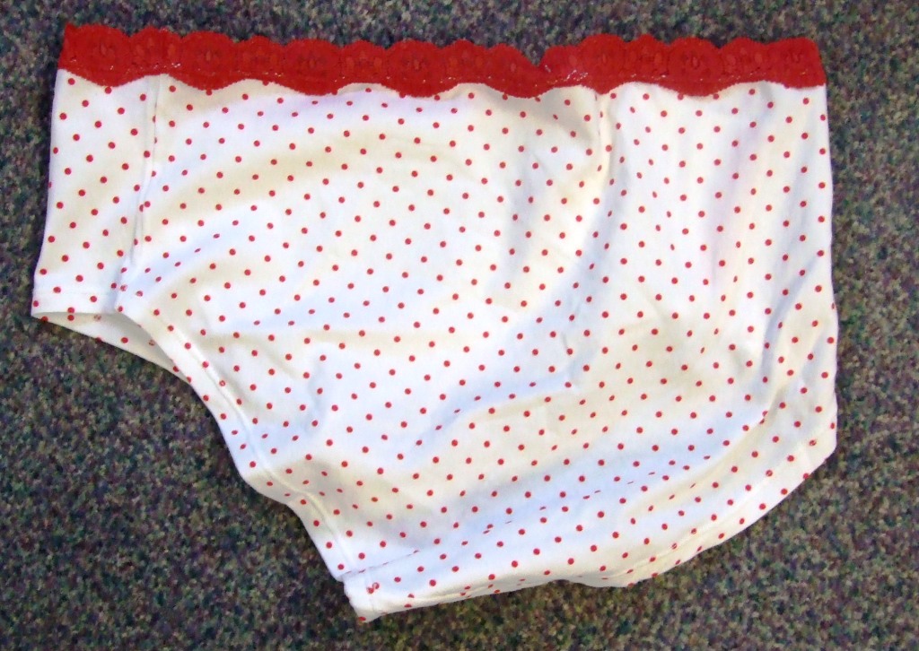 LADIES KNITTED BRIEFS. DESIGNED TO COVER THE LOWER PART OF THE BODY. WITHOUT AN OPENING. WITH ELASTICATION AT THE WAIST. HEMMED. MADE FROM 100% COTTON. CREAM WITH SMALL RED POLKA DOTS WITH LACE TRIM AND BOW.