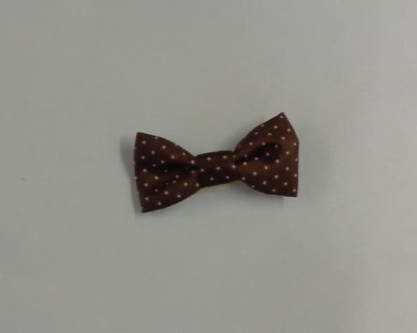 METAL HAIR CLIP WITH A DECROTIVETEXTILE BOW. THE HAIR CLIP IS SILVER IN COLOUR ANDTHE TEXTILE BOW IS BROWN WITH CREAM DOTS.