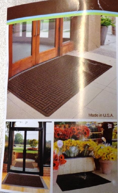 FLOOR MAT. WITH AN UPPER SURFACE OF RECYCLED SYNTHETIC TEXTILE FIBRES IN A PARQUET FLOOR CHANNELLED EFFECT DESIGN. THE FIBRES ARE EMBEDDED IN A RECYCLED RUBBER BASE LAYER. FOR INDOOR OR OUTDOOR USE. MEASURING 91CM X 152CM. PRESENTED WITH A PRINTED PAPER LABEL.