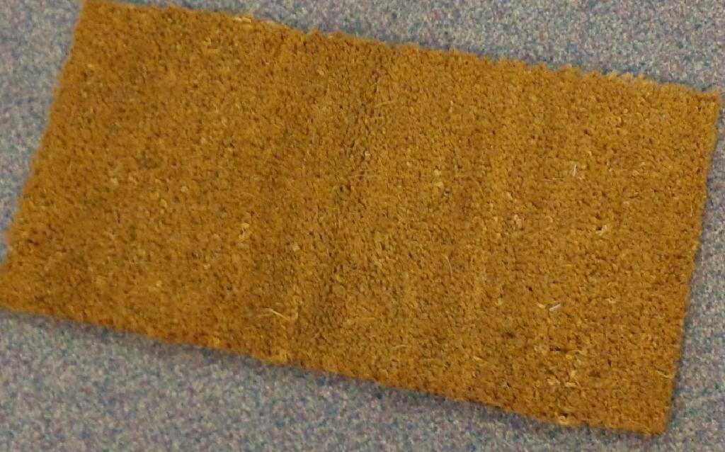 A COIR MAT WITH PVC BACKING. THE COIR YARN IS SPUN AND PLANTED INTO THE BACKING. RECTANGULAR IN SHAPE. DIMENSIONS: 49.5 CM BY 25.5 CM.
