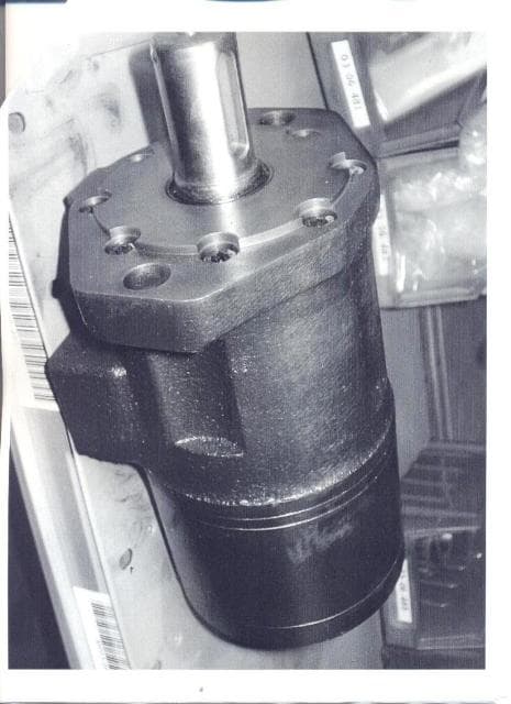A HYDRAULIC MOTOR FOR THE DELIVERY OF HYDRAULIC OIL, MADE OF STEEL AND CAST IRON. ATTACHED TO THE END OF THE MOTOR SHAFT THERE IS A GEAR ADDED WHICH OPERATES A TILT TABLE. THE MOTOR IS NOT LINEAR ACTING WITH CYLINDERS AND IS REVOLUTION BASED. THE MOTOR IS CONSIDERED TO BE A HYDRAULIC FLUID POWER MOTOR. PART OF A HIGH PRESSURE DIE CASTING MACHINE. THE DEVICE IS NOT MACHINE SPECIFIC AND CAN BE USED ON OTHER MACHINES.