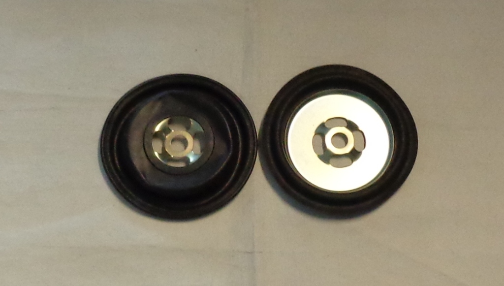 A NITRILE RUBBER AND METAL DIAPHRAGM DESIGNED & USED SOLELY IN A GAS REGULATOR. DIAPHRAGM IS PART OF AN ASSEMBLY USED TO REDUCE PRESSURE. MANUFACTURED BY COMPRESSION MOULDING (FORMING) TO A SHAPE AND CONSTRUCTION DETERMINED BY THE REGULATOR. OUTER SHAPED RUBBER DISC WITH RAISED LIP AND CENTRAL HOLE. SHAPED METAL INNER DISC WITH FIVE HOLES LOCATED CENTRALLY,  RUBBER IS ATTACHED TO THE METAL IN 3 PLACES. DIAMETER: RUBBER APPROXIMATELY 12.5CM. METAL APPROXIMATELY 9CM.