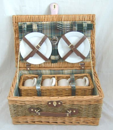 WICKER  PICNIC BASKET. WITH HANDLE. THE LID IS INTERNALLY FITTED WITH STRAPS TO HOLD/SECURE THE CONTENTS. THE BASKET CONTAINS A SET OF DINNERWARE  FOR FOUR PEOPLE. DINNERWARE SET COMPRISES OF 4 PORCELAIN 7 INCH PLATES. 4 PORCELAIN MUGS  (WITH WILLOW HOLDER). 4 STAINLESS STEEL KNIVES, FORKS AND SPOONS.