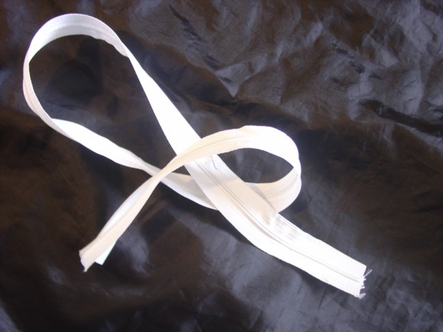 ZIP FASTENER. TWO SIDE STRIPS ARE OF TEXTILE MATERIAL, ONE EDGE OF EACH STRIP BEING FITTED WITH PLASTIC SCOOPS WHICH ARE MADE TO INTERLOCK BY MEANS OF A METAL SLIDE RUNNER.