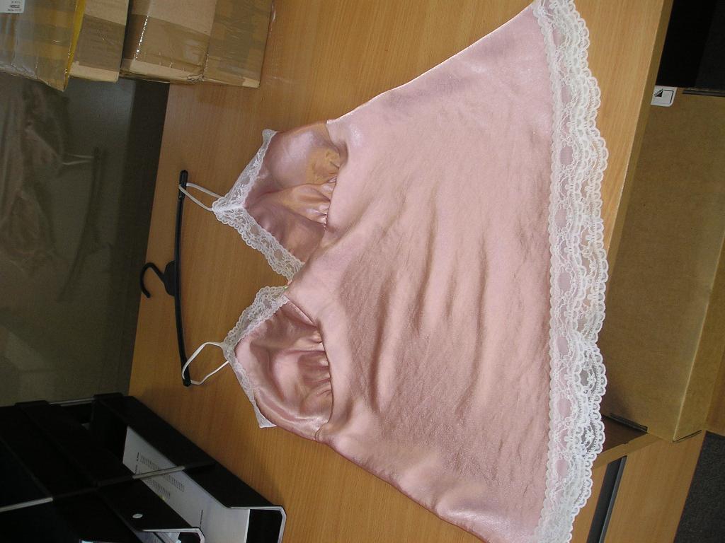 A WOVEN FULL LENGTH SLIP FOR LADIES. WITH A V-NECK. WITH LACE TRIM TO NECKLINE AND HEM. WITH SHOULDER STRAPS. OF SYNTHETIC FIBRES.