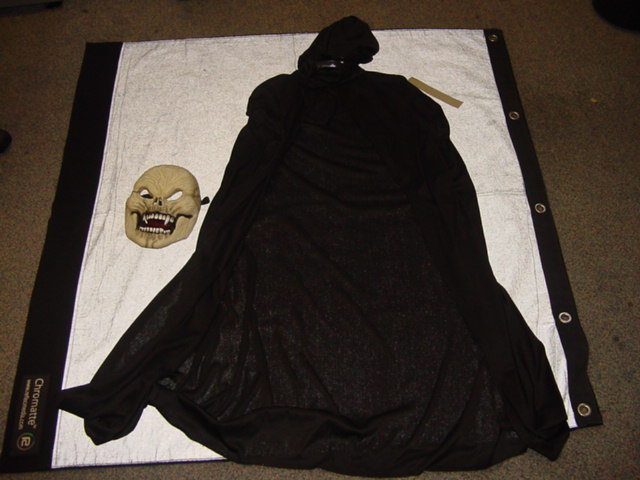 A KNITTED FANCY DRESS FULL LENGTH CLOAK FOR UNISEX.  DESIGNED TO COVER THE BODY FROM THE SHOULDERS TO BELOW THE KNEE.   FITTED AT THE SHOULDERS.  WITH A COMPLETE OPENING.  WITH A ROUND NECK WITH TIE FASTENING.  WITH HOOD.  OVERLOCKED AT EDGES.  100 PERCENT POLYESTER.  PACKAGED ON A PLASTIC HANGER  WITH A PLASTIC SKULL MASK ACCESSORY IN A POLYBAG WITH CARDBOARD FOR RETAIL SALE.